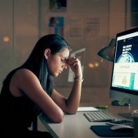 a woman with her head in hand in front of a computer