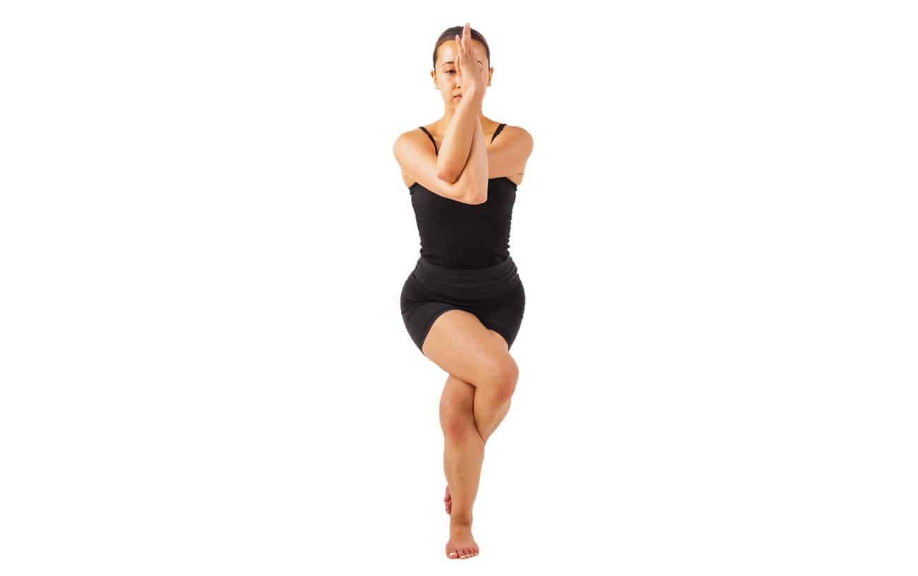 a woman wearing black yoga clothes doing eagle pose