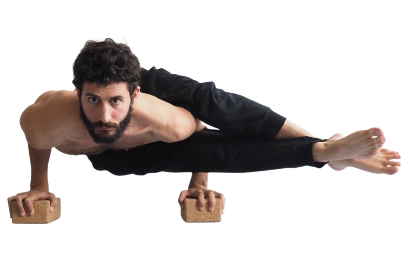 a man wearing black yoga clothes doing eight angle pose on blocks