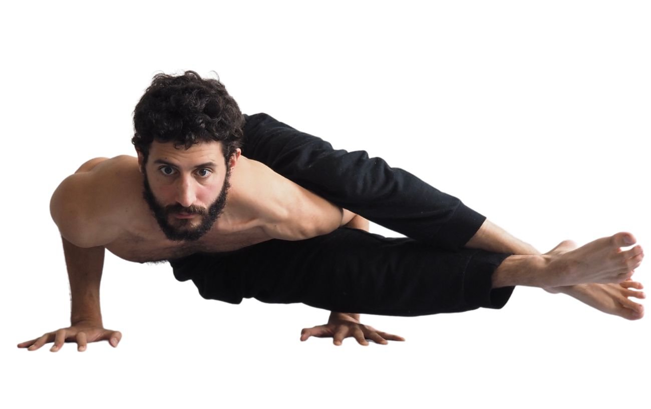 a man wearing black yoga clothes doing eight angle pose 