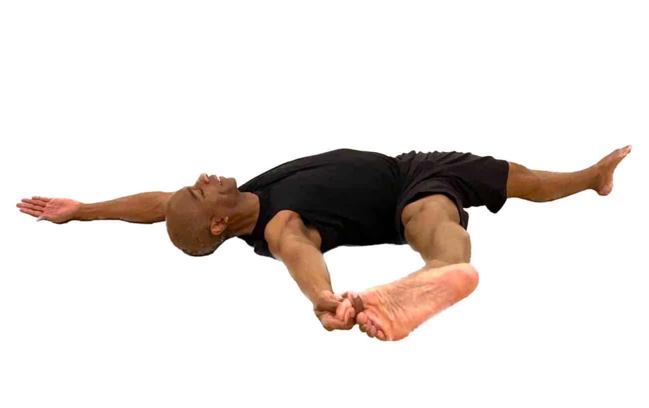 a man wears black and does reclined extended hand to big toe pose