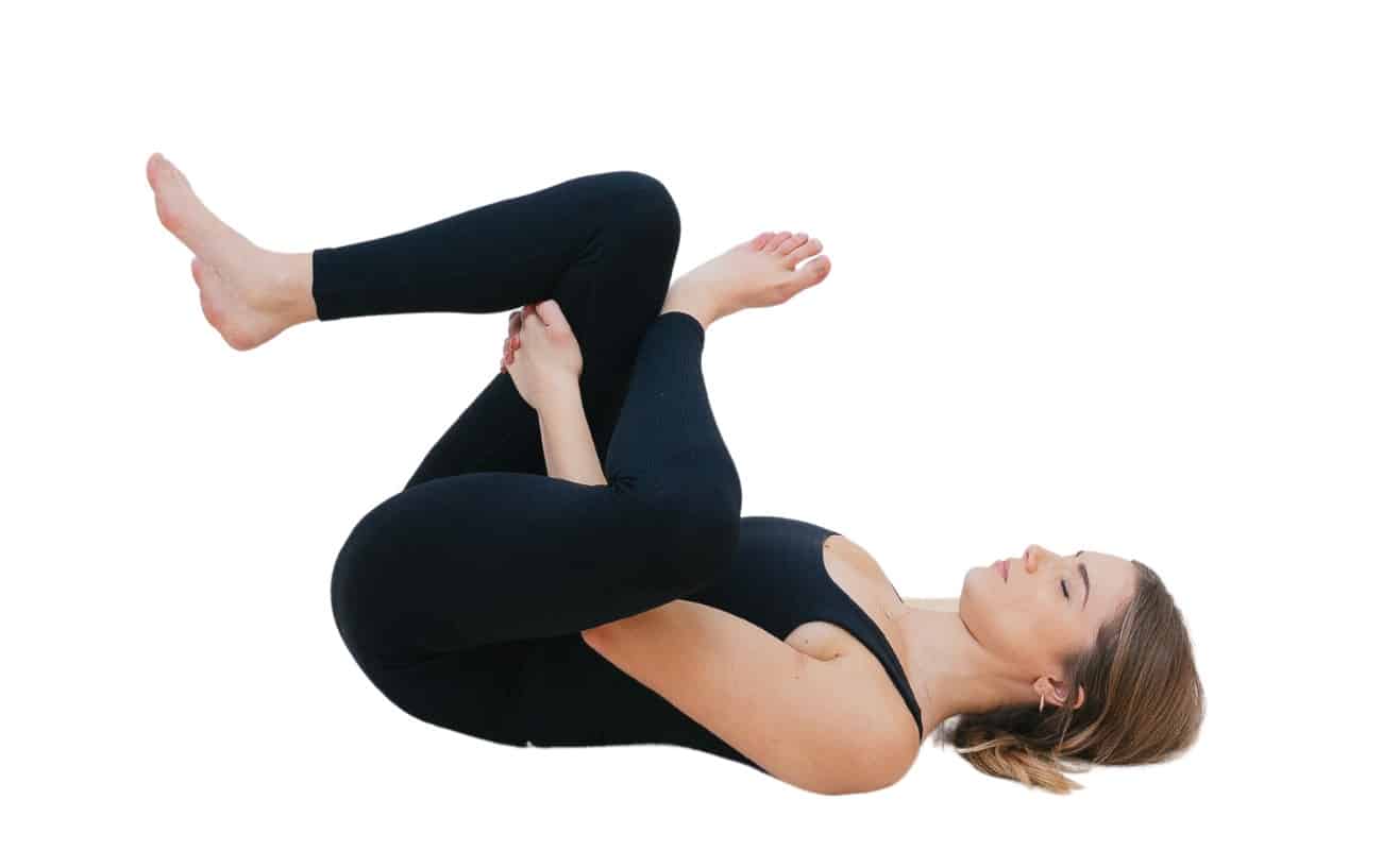 woman wearing black yoga clothes does a Reclining Pigeon Pose