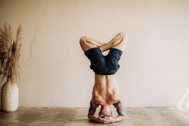 a shirtless man doing a headstand