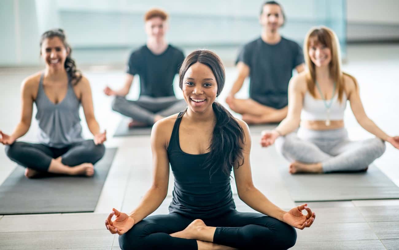 five people practice a yoga routine together