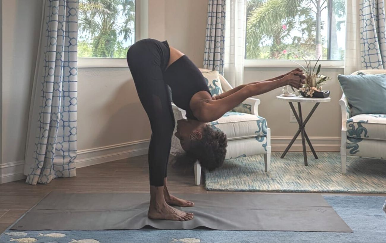 a woman wearing black yoga clothes doing yoga stretches in her living room