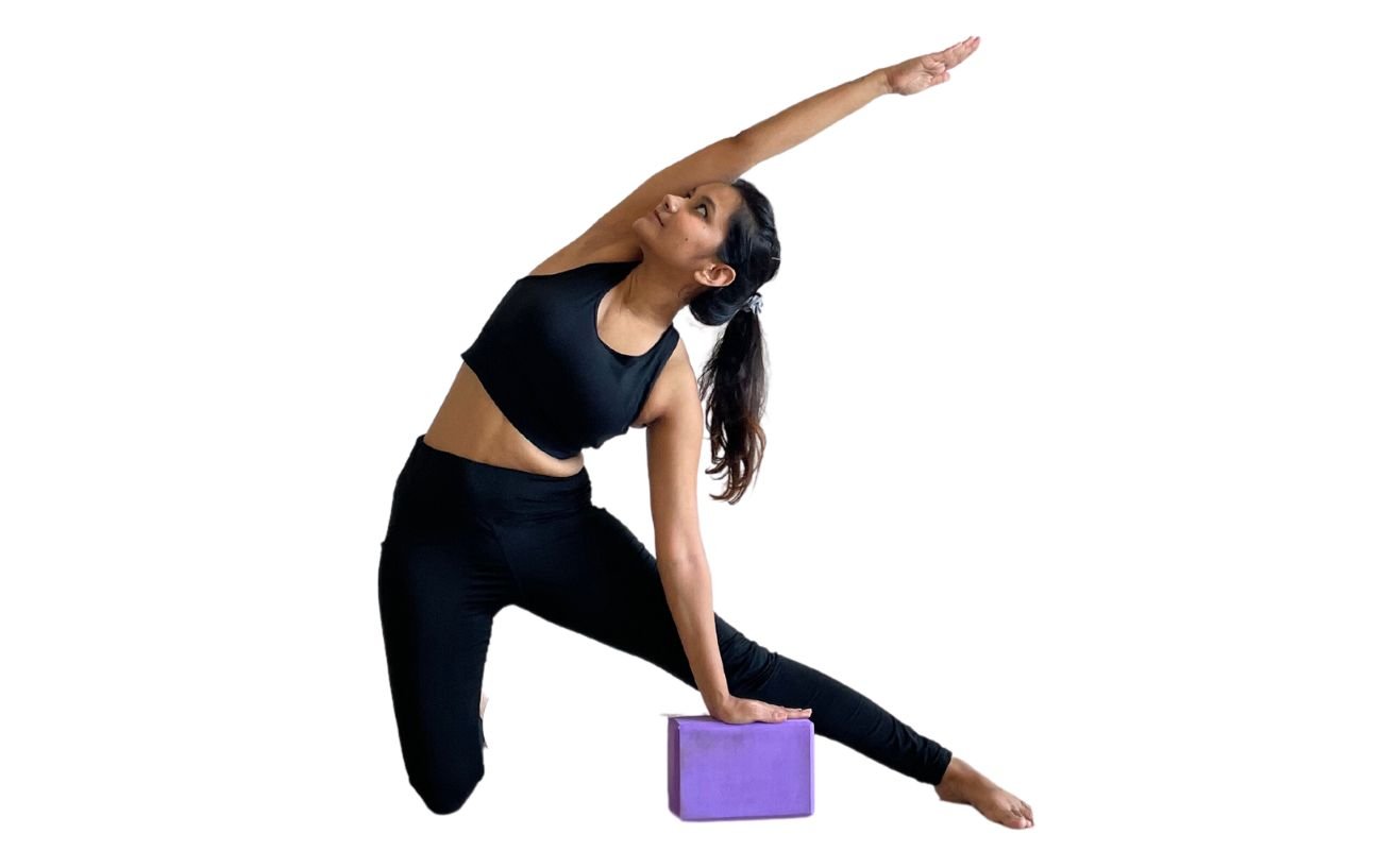 a woman wearing black yoga clothes doing gate pose with a block