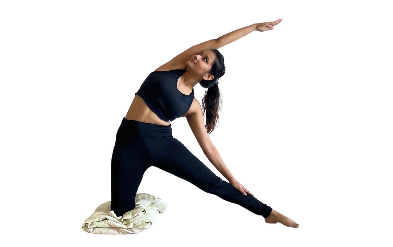 a woman wearing black yoga clothes doing gate pose on a blanket