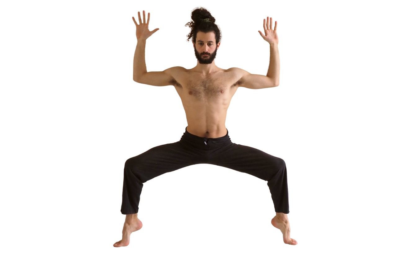 a man wearing black yoga trousers doing goddess pose on his toes