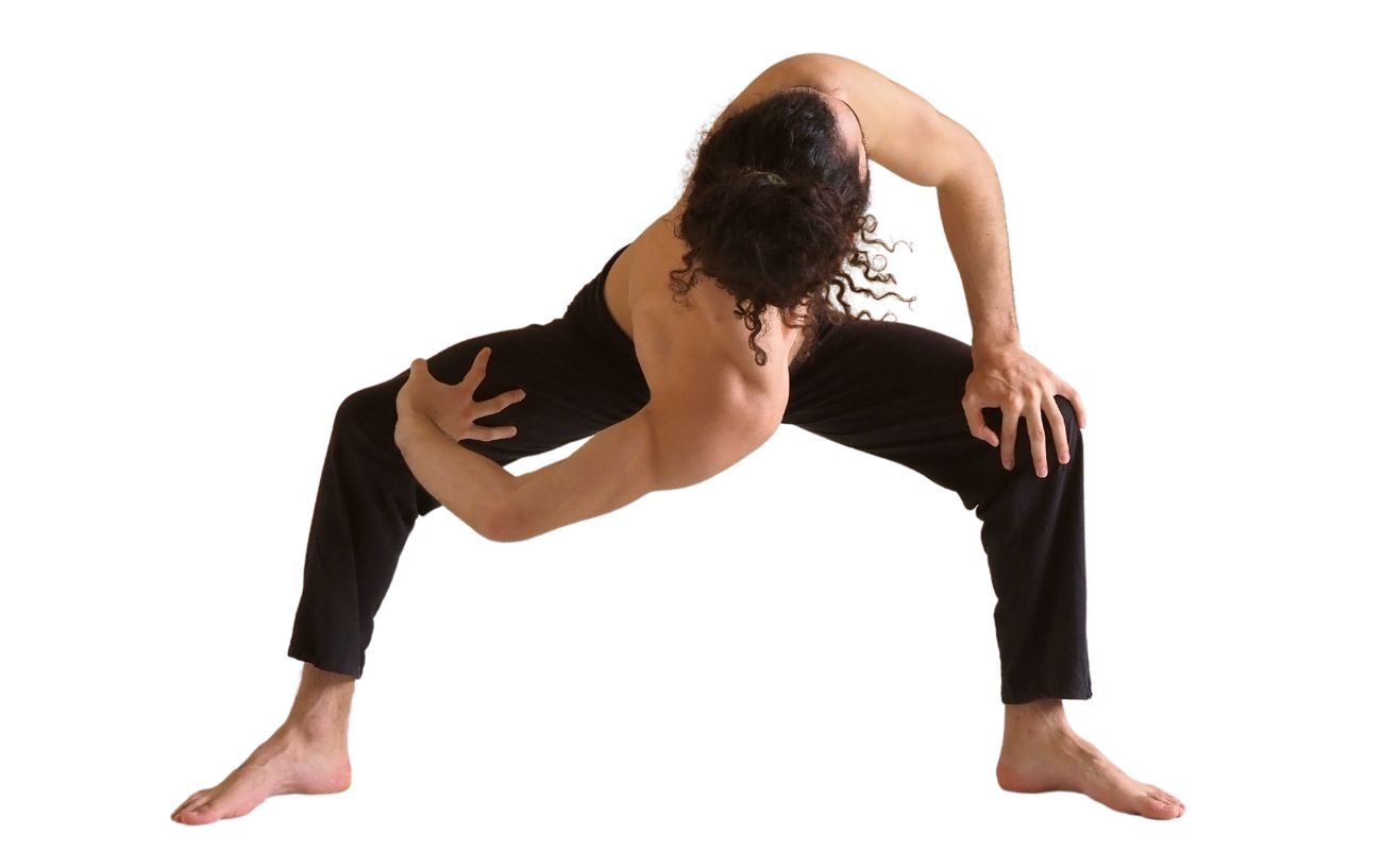 a man wearing black yoga trousers doing goddess pose with a twist