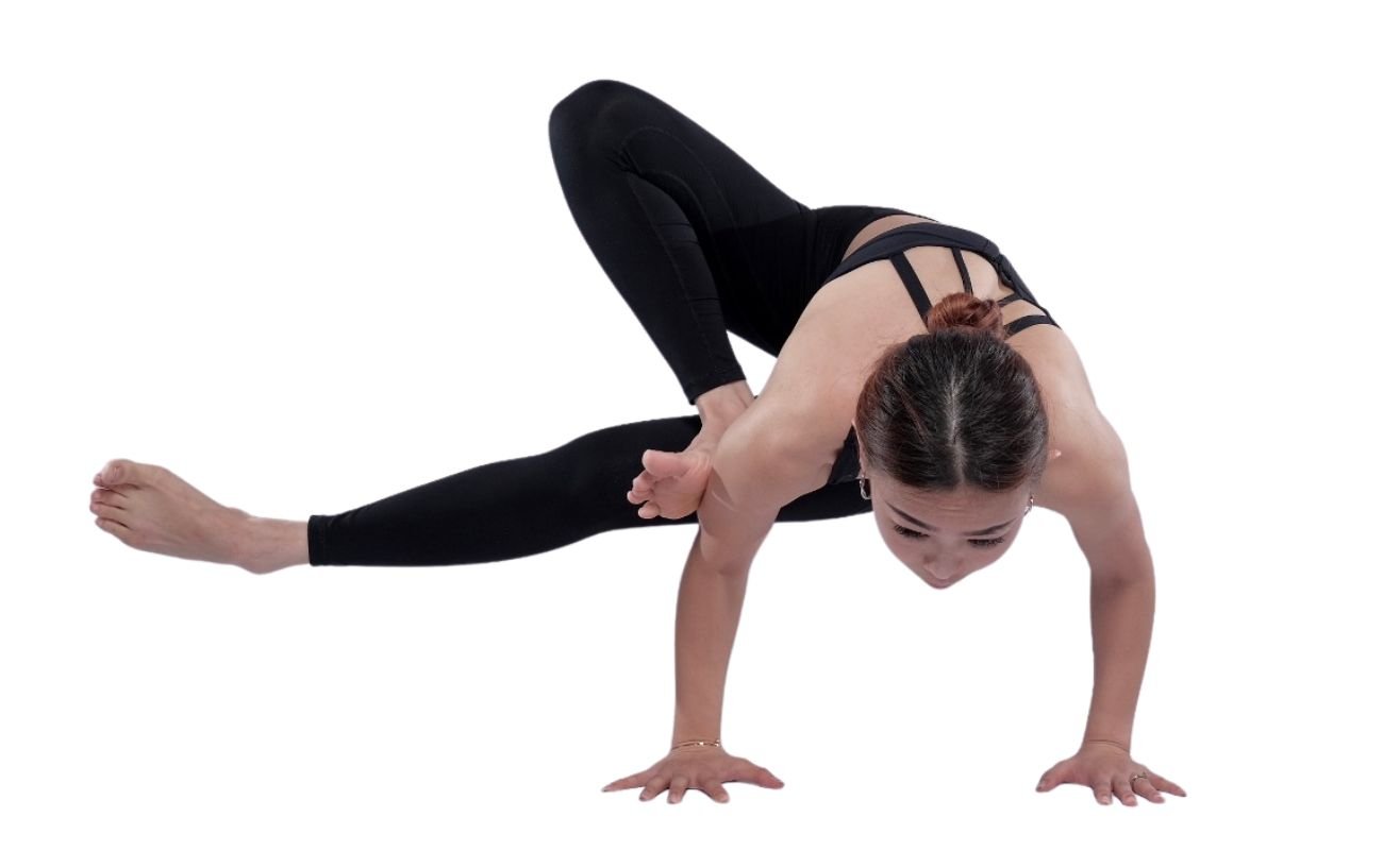 a woman wearing black yoga clothes doing grasshopper pose