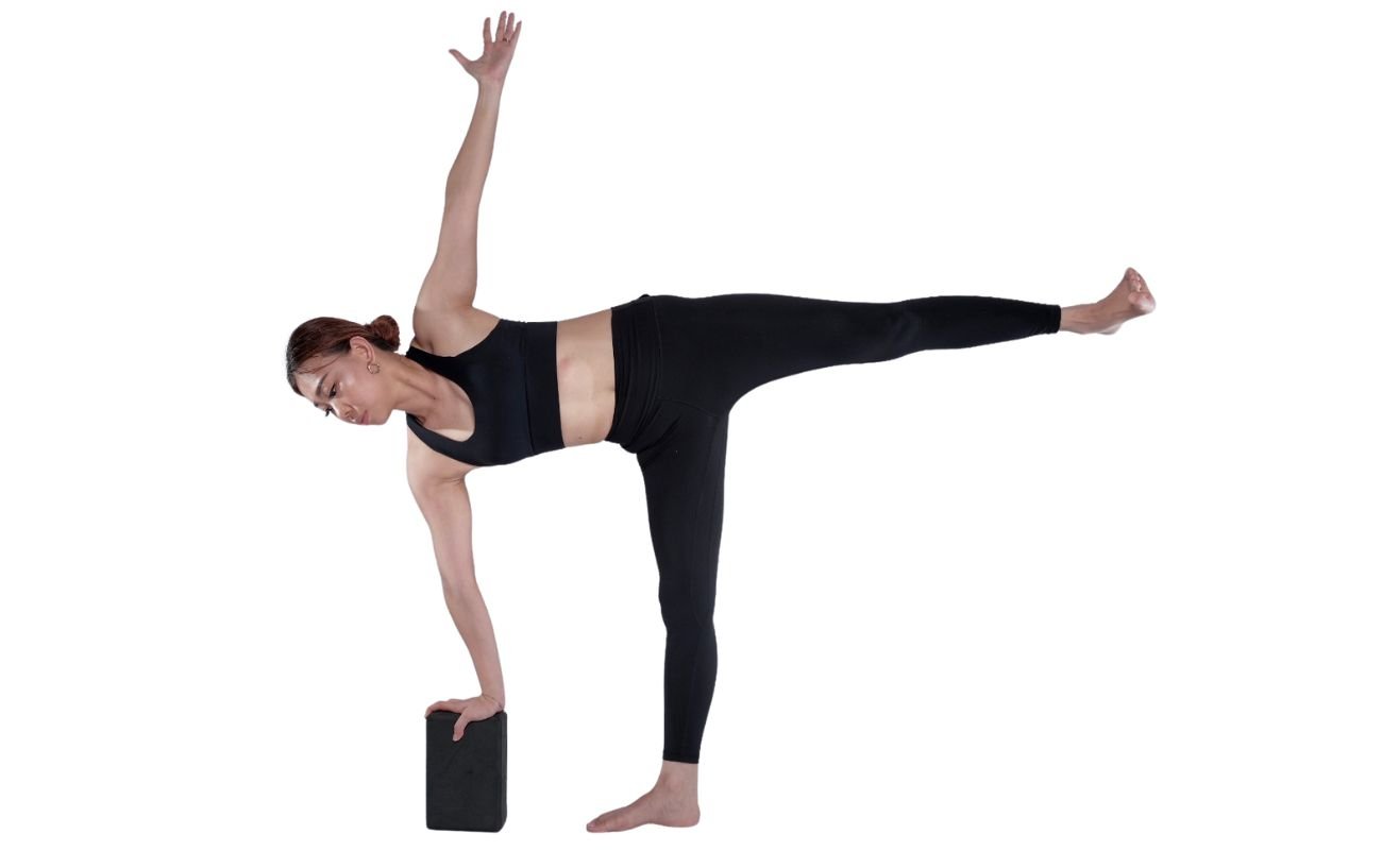 a woman wearing black yoga clothes doing half moon pose with a block