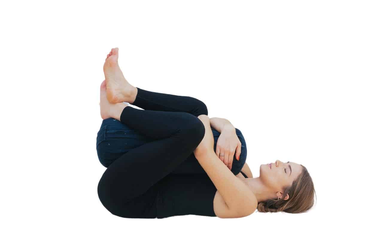 woman doing happy baby pose hugging a bolster