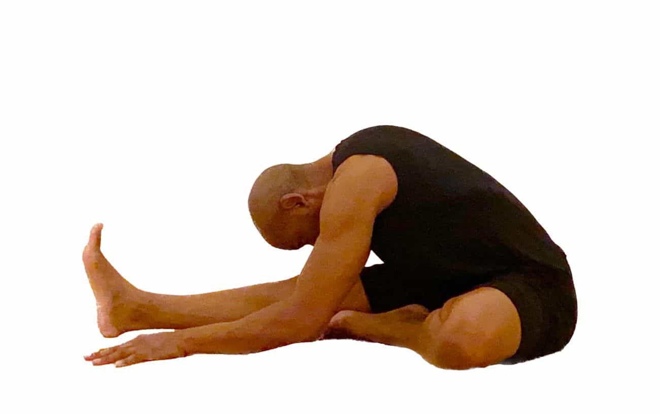 a man wearing black yoga clothes doing head to knee pose