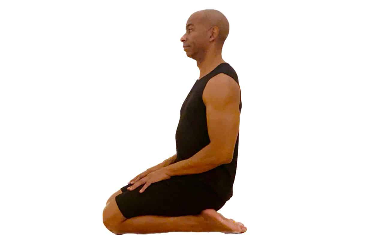 a man wearing black yoga clothes doing thunderbolt pose side on