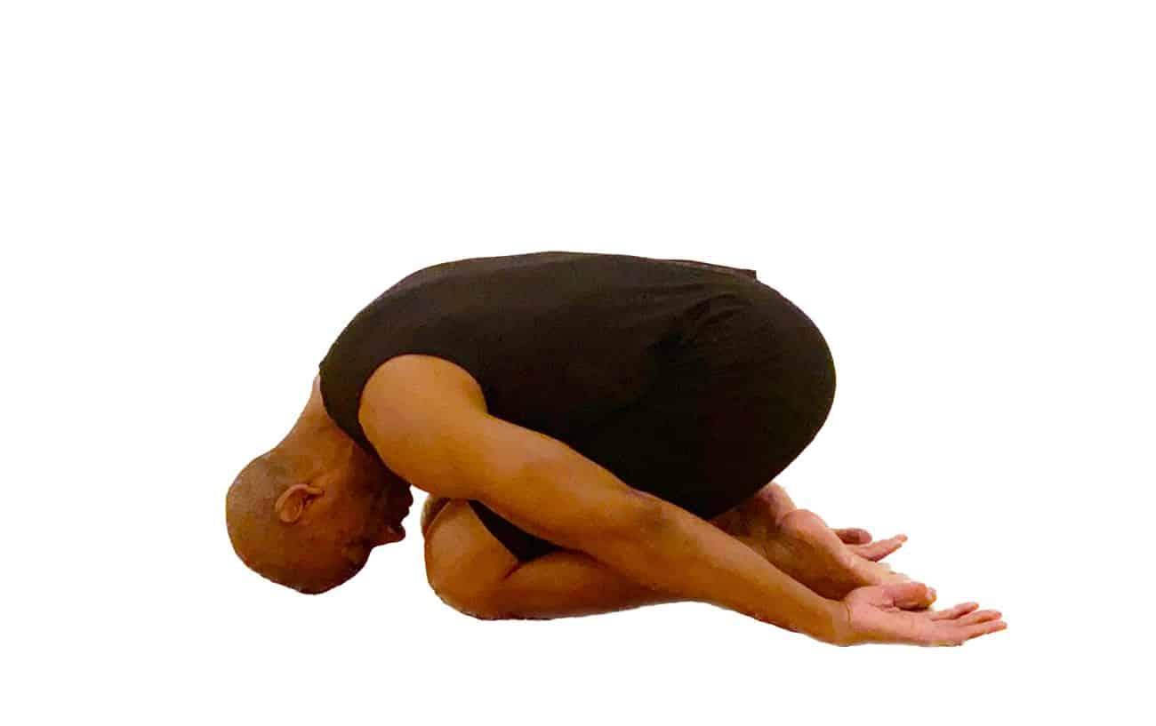 a man wearing black yoga clothes doing hero pose with his torso over his thighs