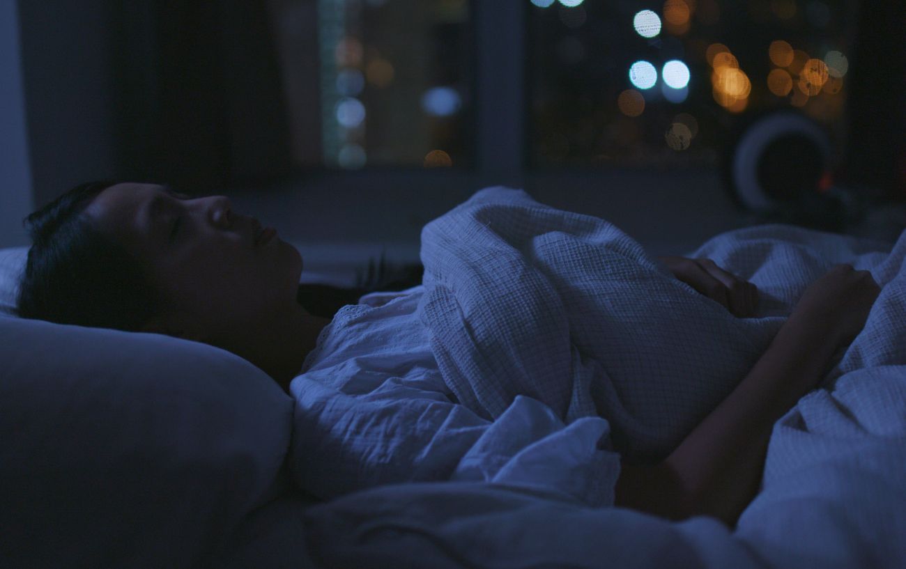 A woman lying in bed in the dark