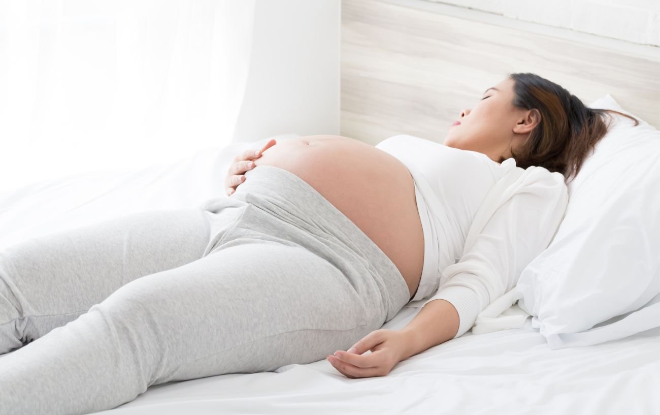 A pregnant woman laying in bed.