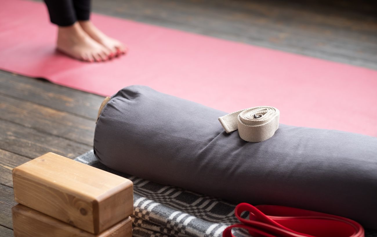 Someone standing on a pink yoga mat with props next to them.