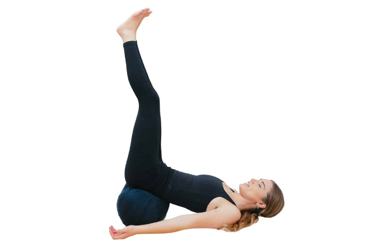 woman doing legs up the wall yoga pose with a bolster under her hips