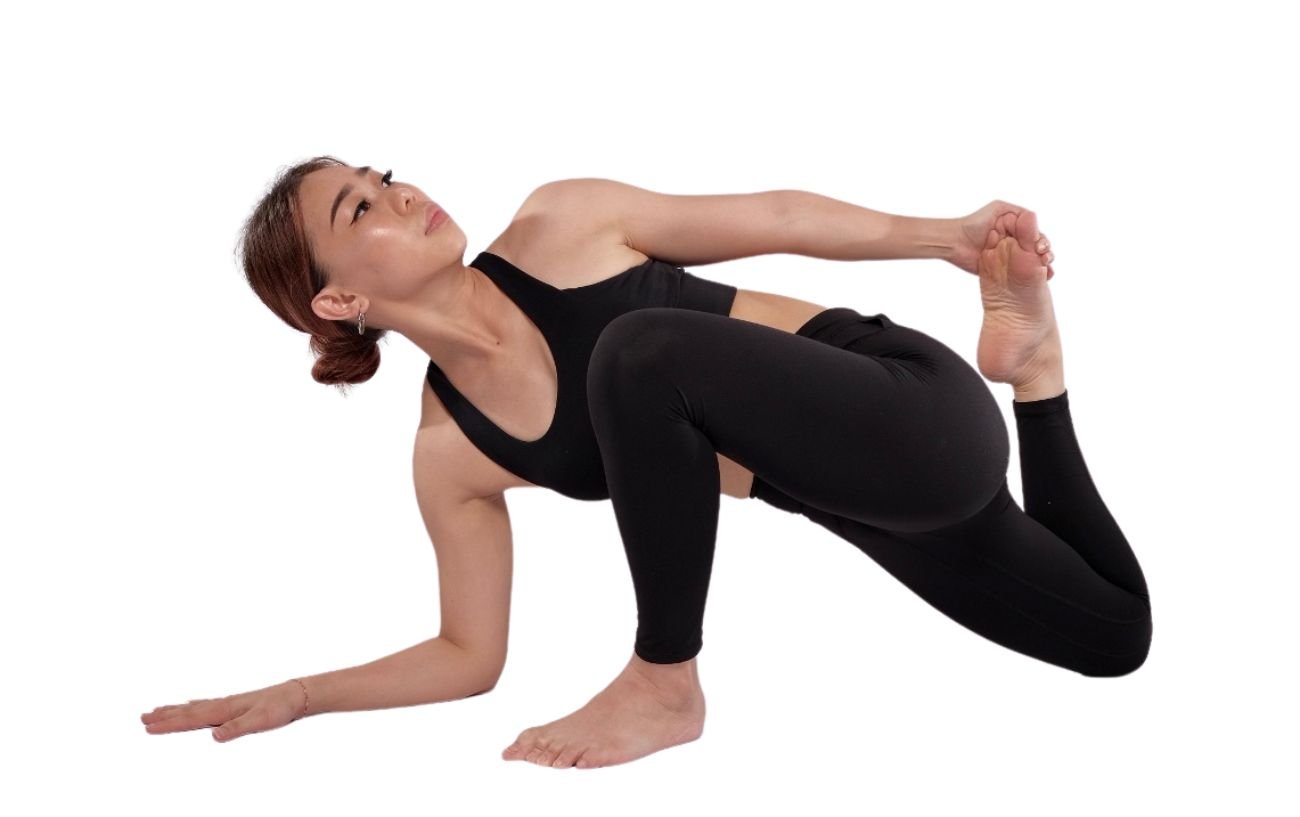 a woman wearing black yoga clothes doing lizard pose with a quad stretch