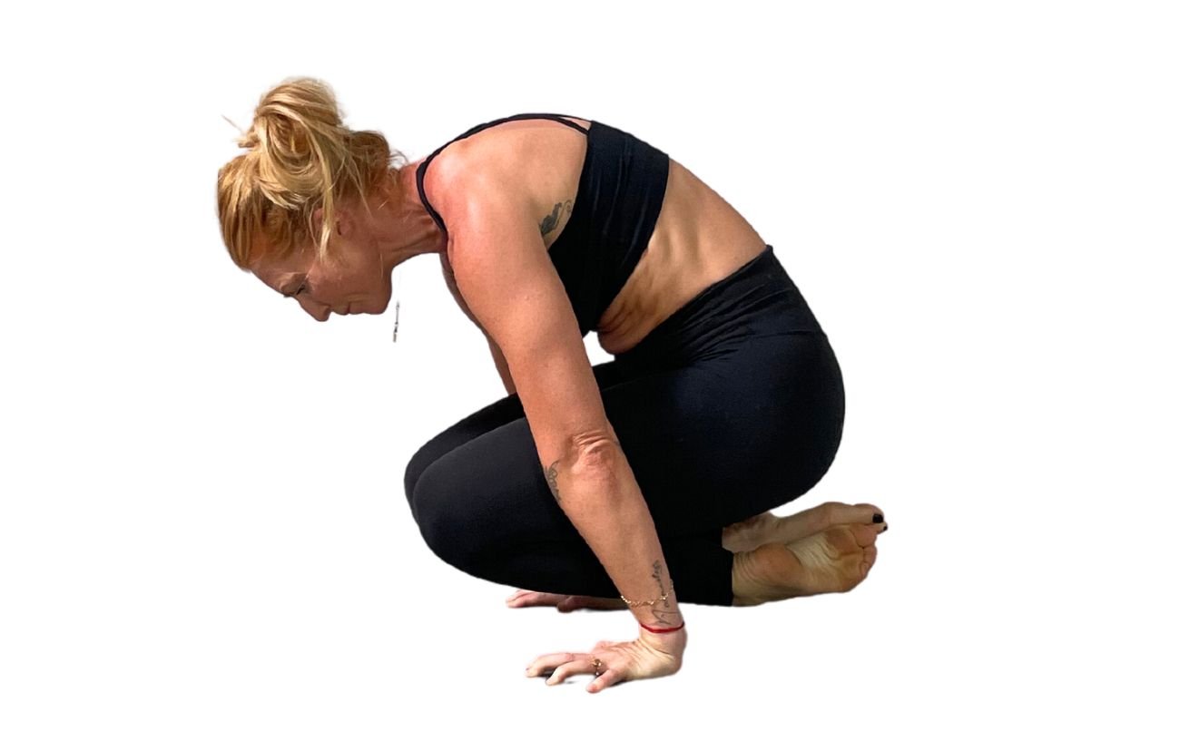 a woman wearing black yoga clothes doing lolasana