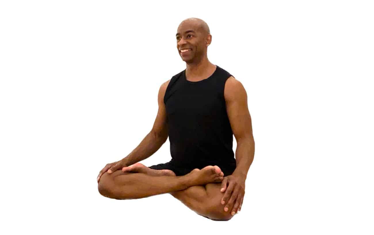 a man wearing black yoga clothes sitting in lotus pose