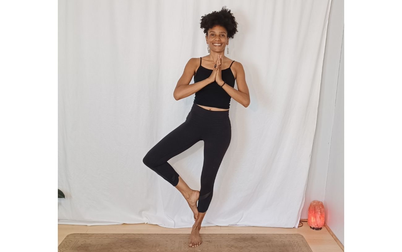 a woman doing a tree pose variation against a white background