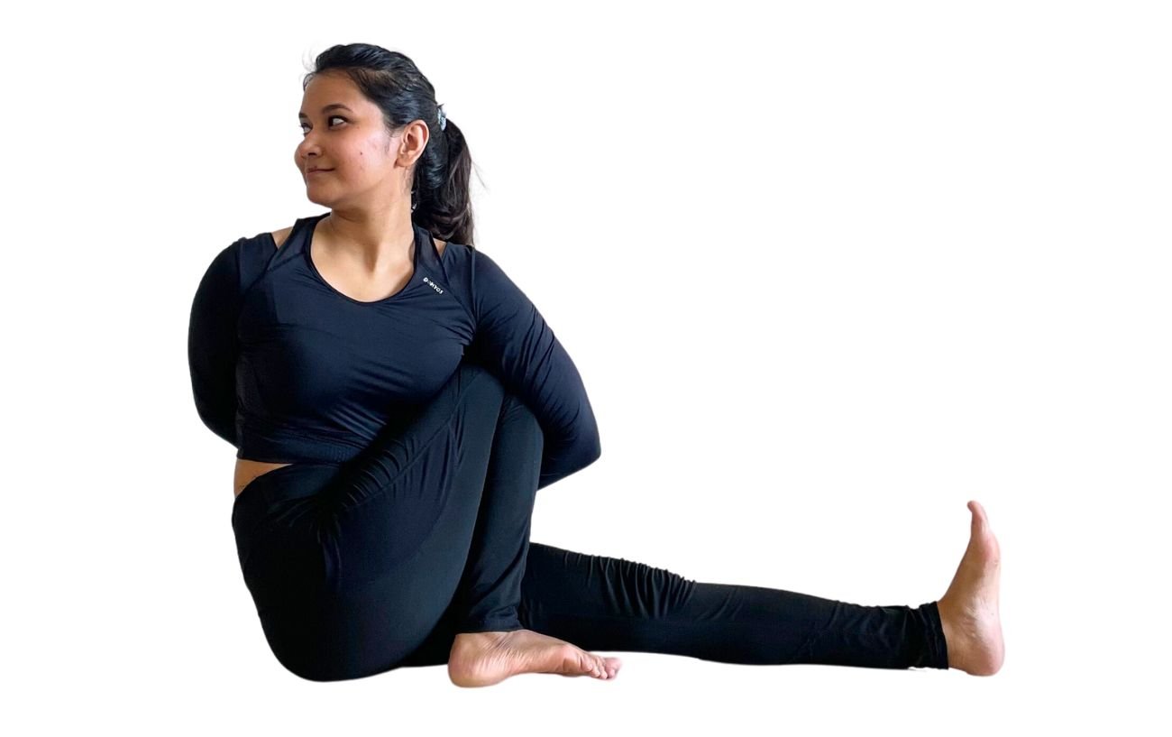  a woman wearing black yoga clothes doing Marichyasana C