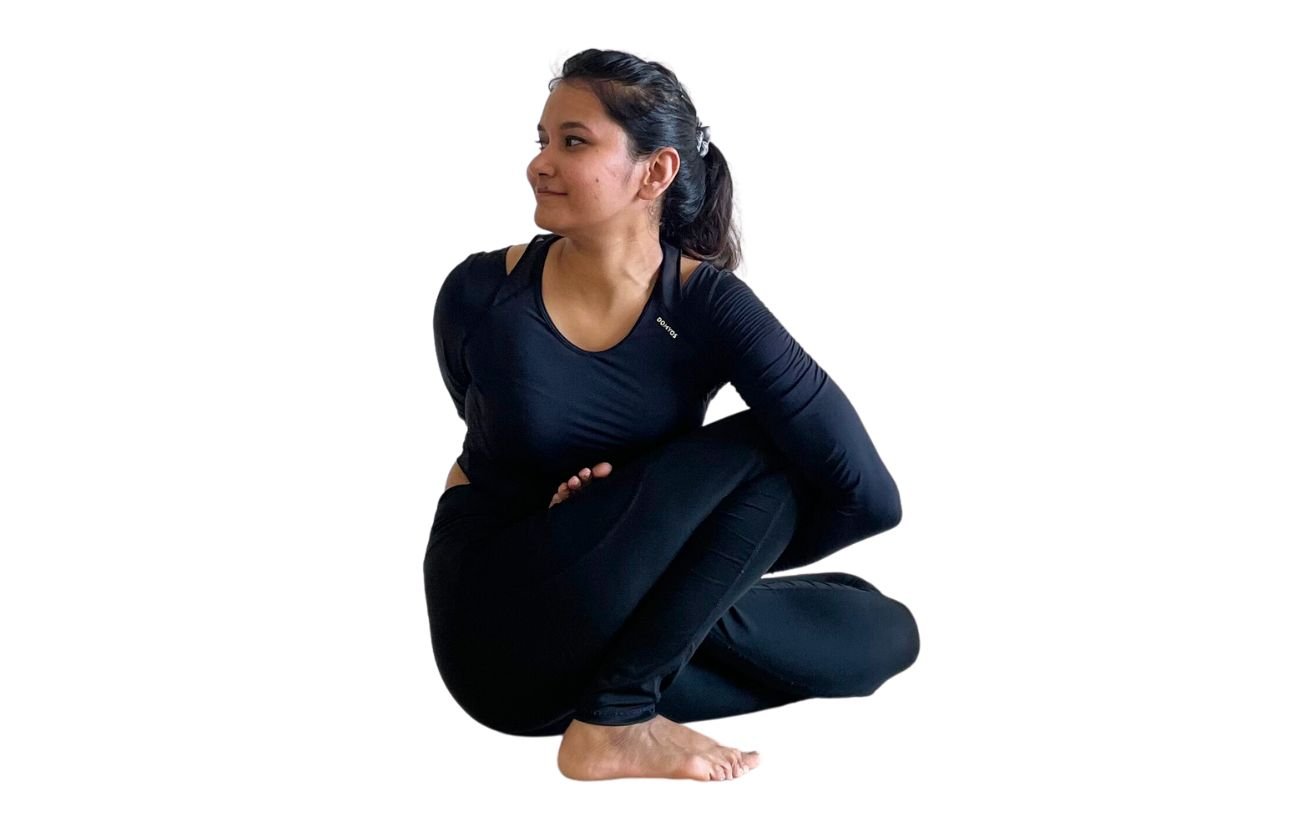 a woman wearing black yoga clothes doing Marichyasana D