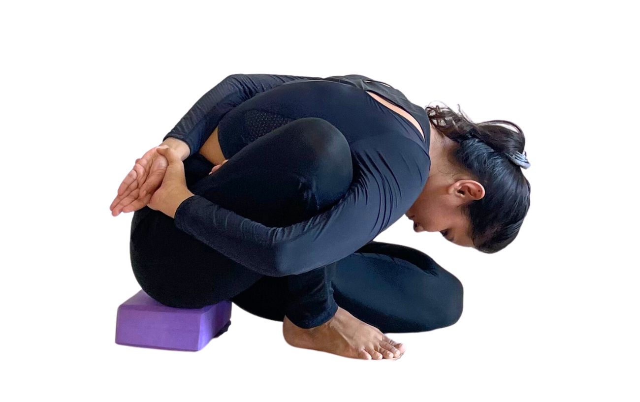 a woman doing Marichyasana B sitting on a block