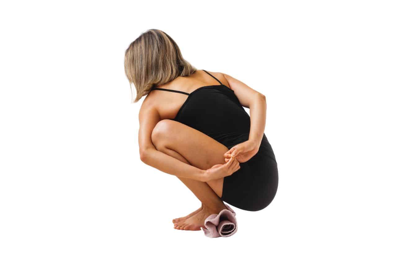 woman doing noose pose with her heels elevated on a towel