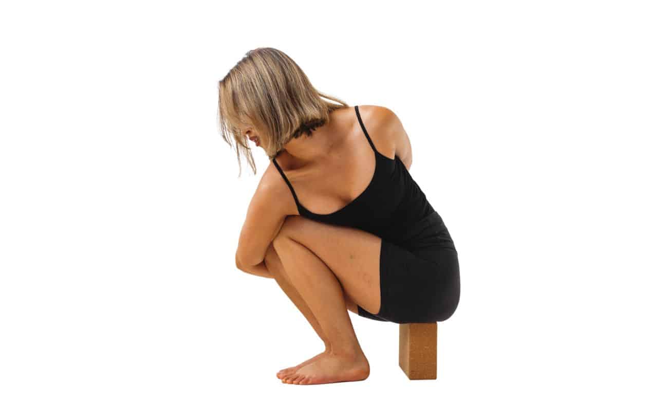 woman wearing black yoga clothes in noose pose on a yoga block