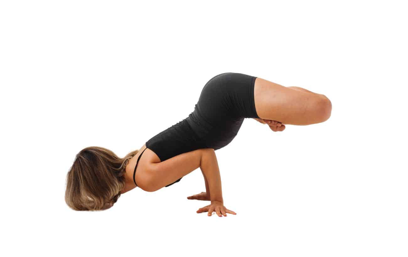 a woman wearing black yoga clothes in peacock pose with her legs in lotus