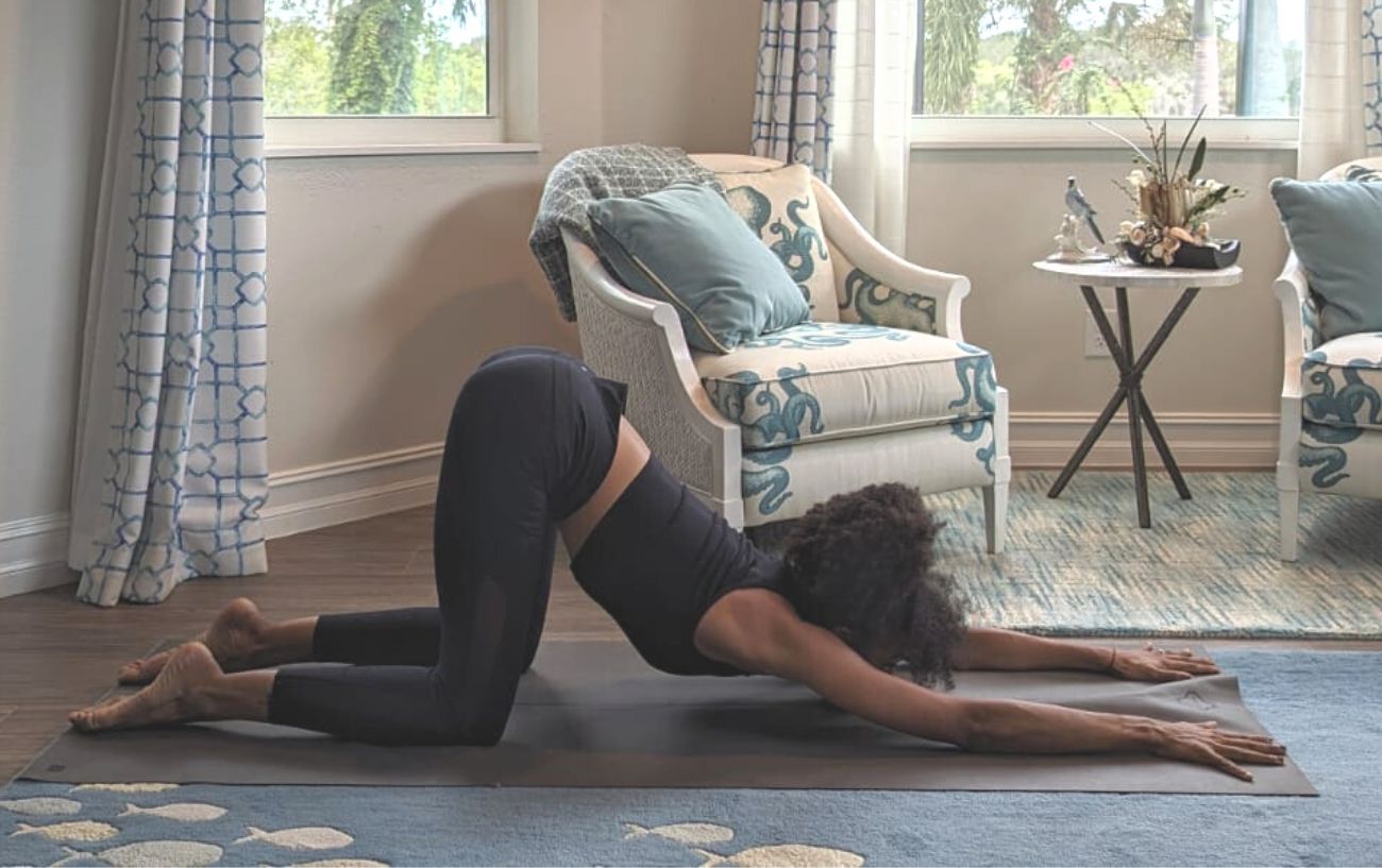 a woman wearing black yoga clothes doing yoga in her living room