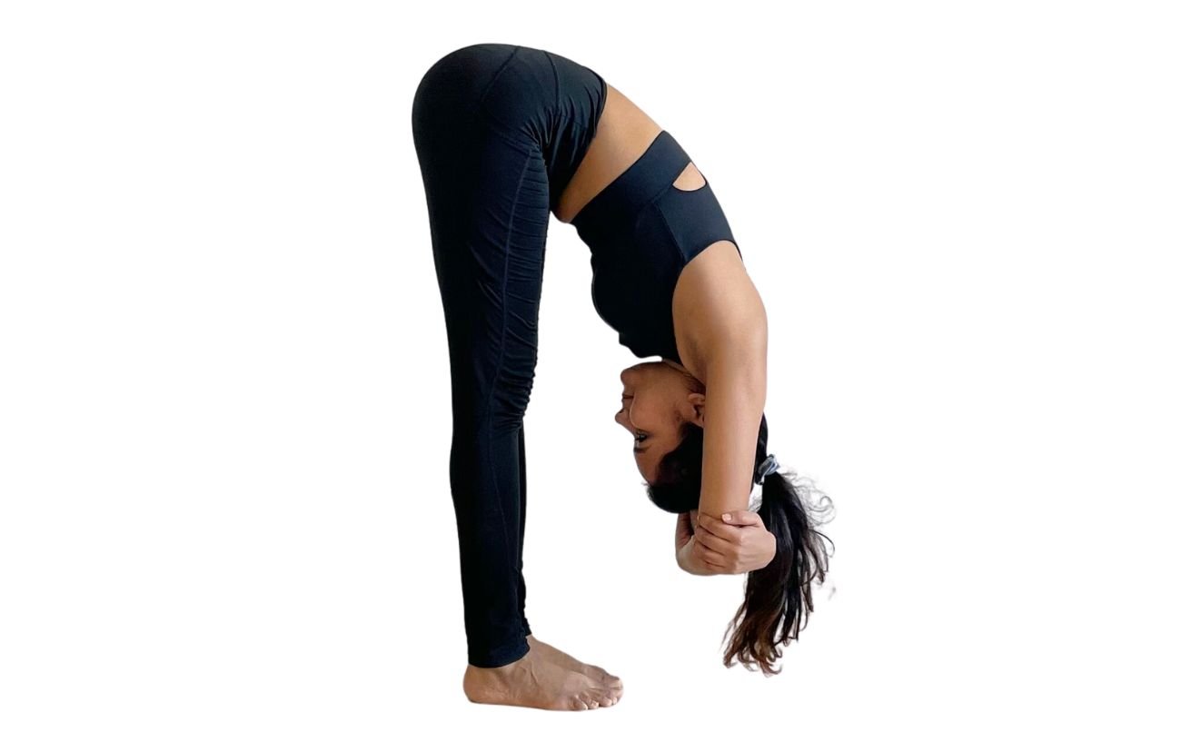 a woman wearing black yoga clothes doing ragdoll pose