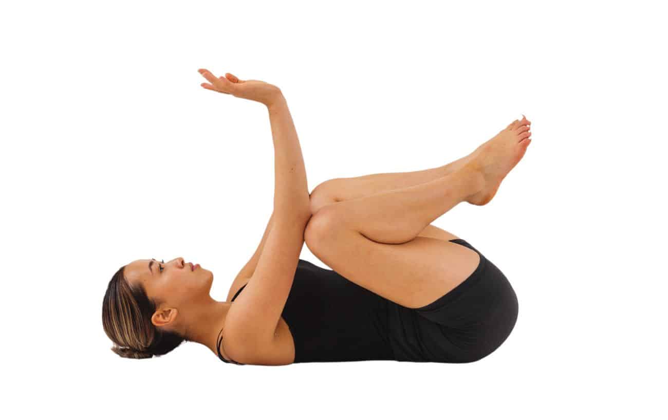 a woman wearing black yoga clothes doing reclined crow pose