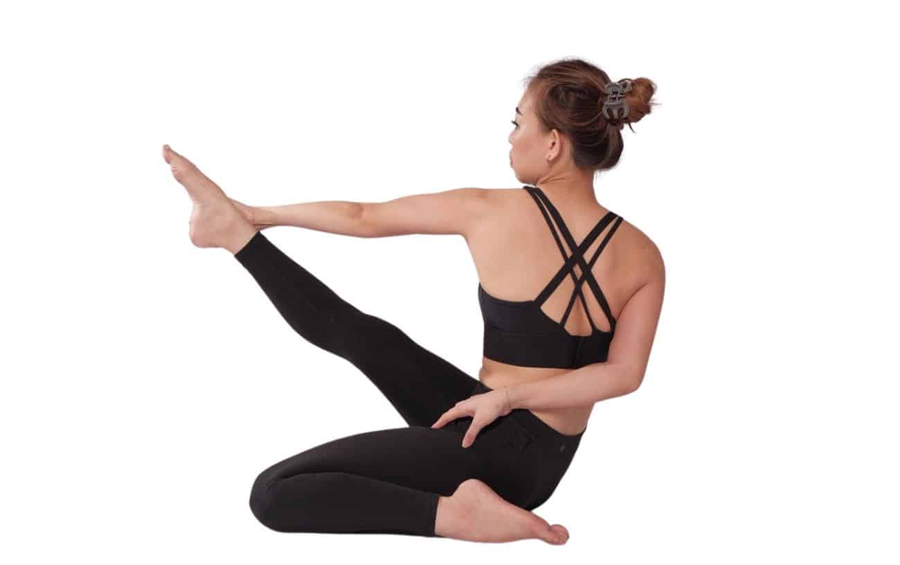 a woman wearing black yoga clothes doing revolved heron pose