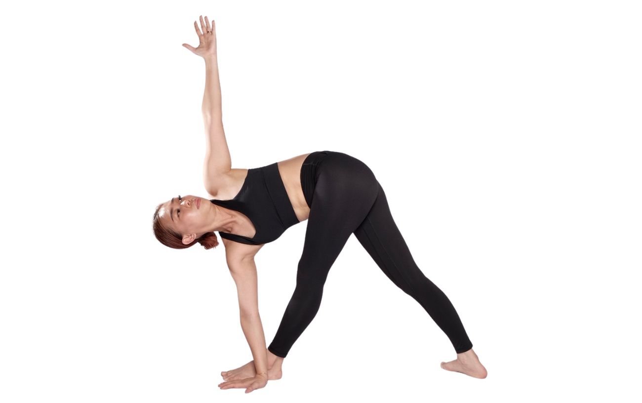 a woman wearing black yoga clothes in revolved triangle pose