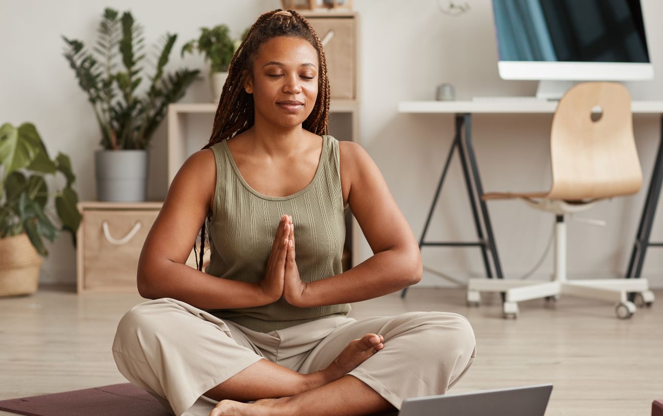 A woman sitting cross legged on the floor in meditation.