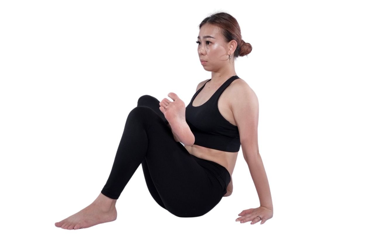 a woman wearing black yoga clothes doing seated figure four stretch