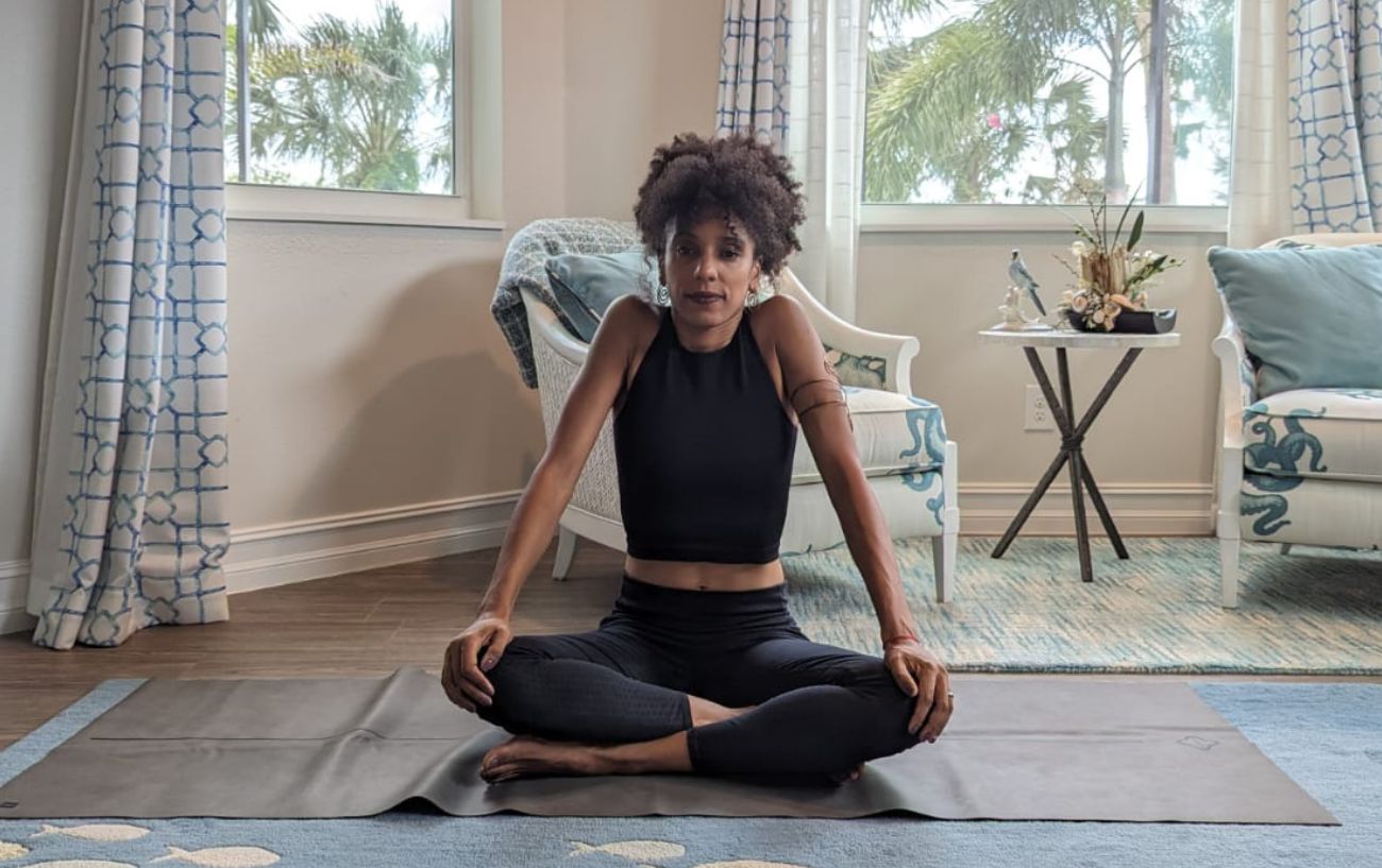 a woman wearing black yoga clothes doing yoga neck stretches cross legged in her living room