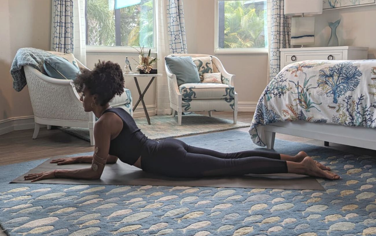 a woman doing sphinx pose in black yoga clothes in a living room