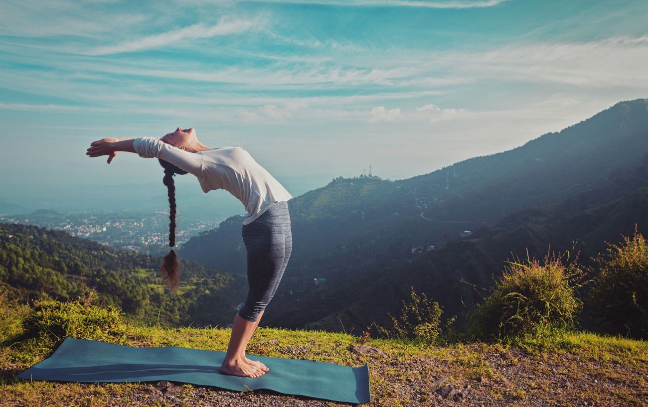 a woman doing sun salutations on a yoga mat on a mountain 