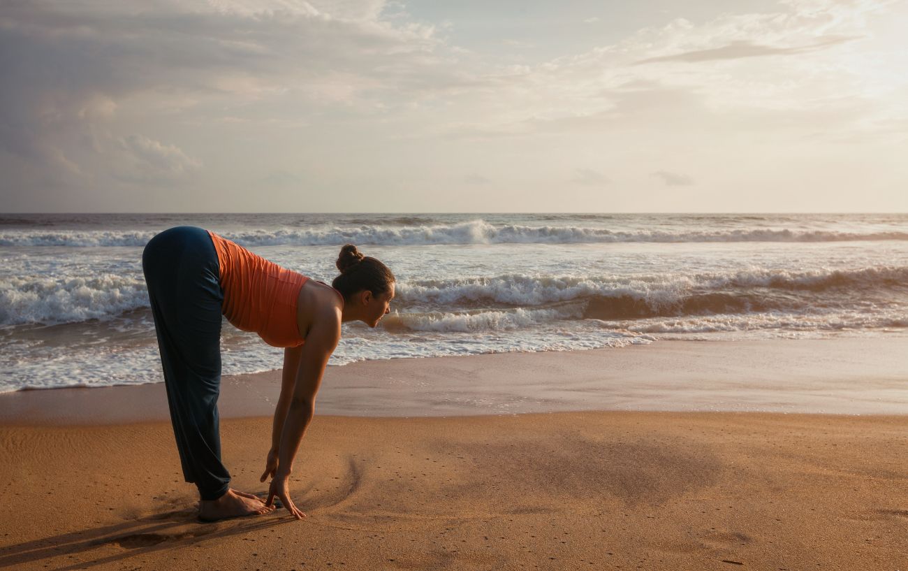 a woman doing sun salutations on a beach