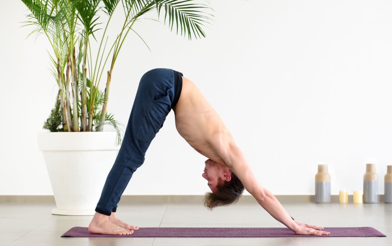 a man doing downward dog on a yoga mat