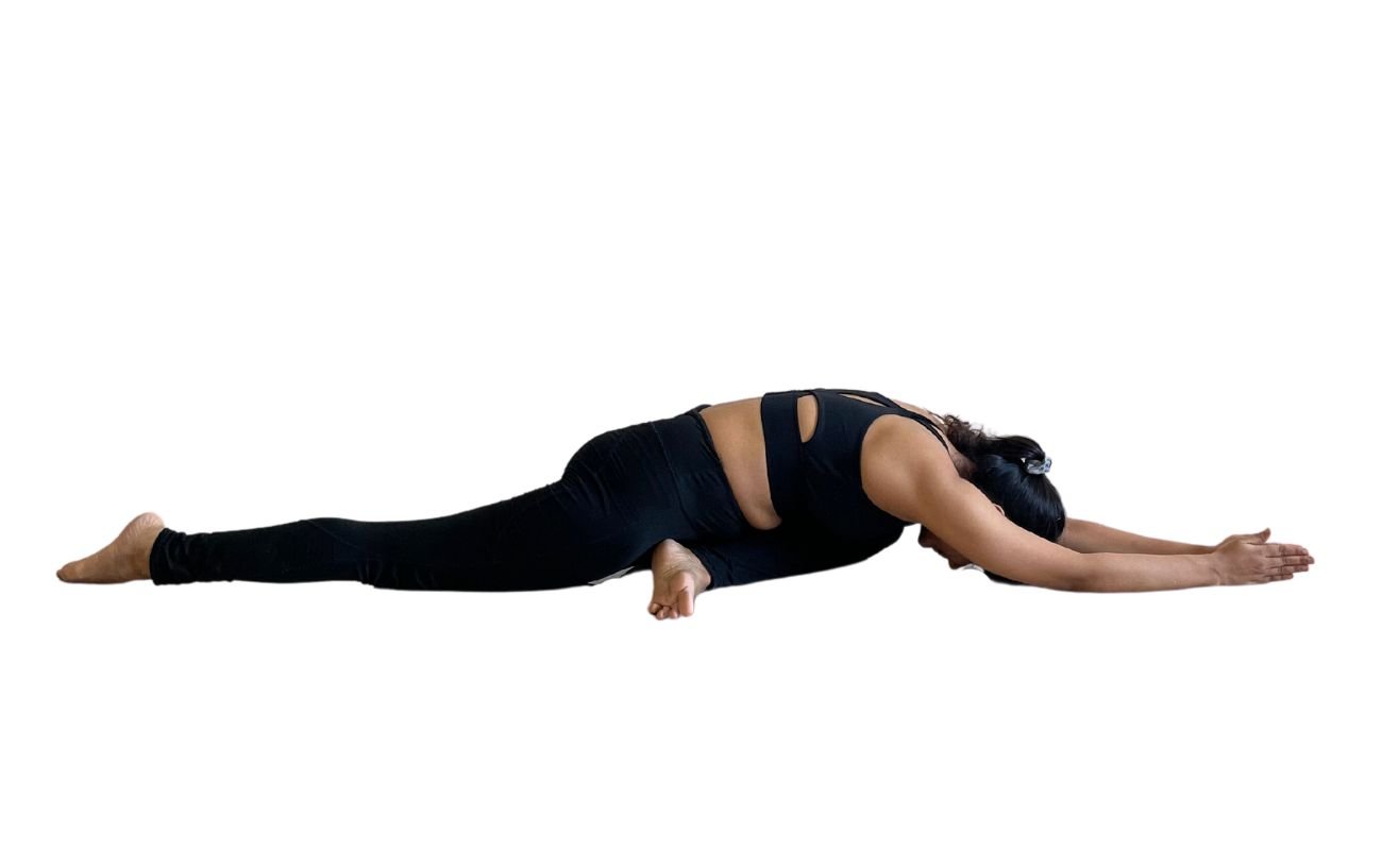 a woman wearing black yoga clothes in sleeping swan pose