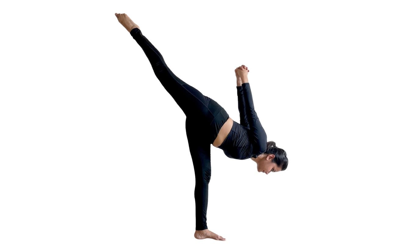 a woman wearing black yoga clothes doing toppling tree