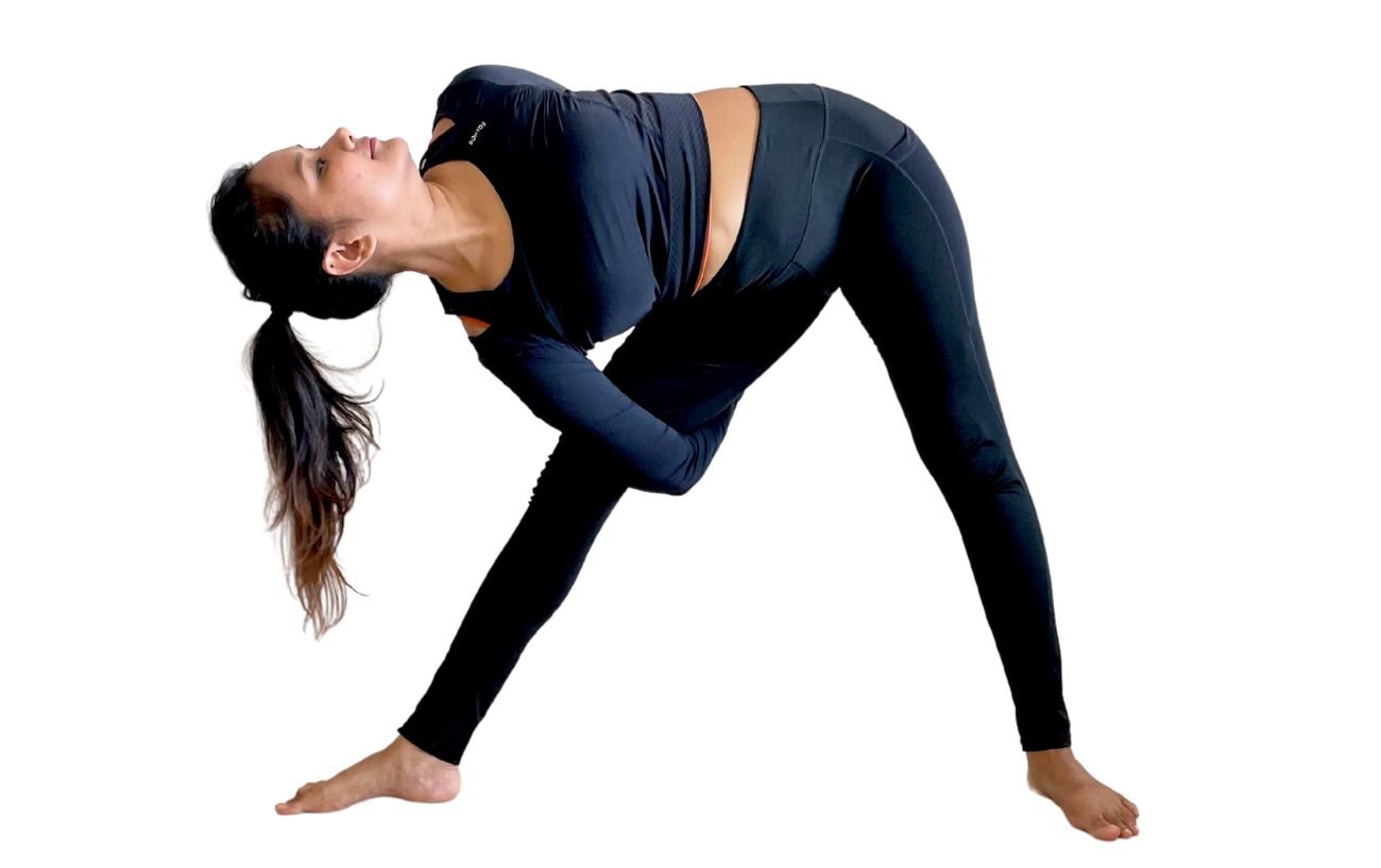 a woman wearing black yoga clothes doing triangle pose with a bind