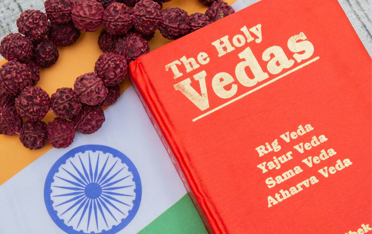 a red book of the holy vedas, an indian flag, and mala beads