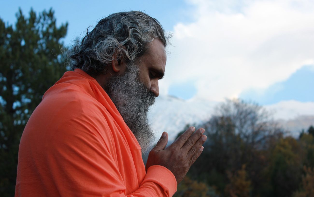 a man in an orange robe with his hands in prayer